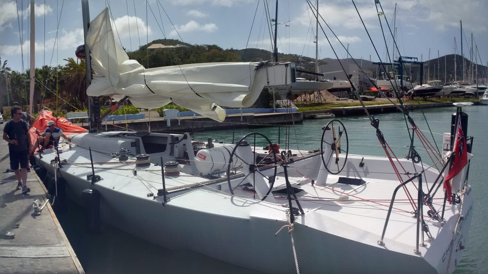 Challenger tied up in Antigua marina, wide shot showing the boat and dock with Ken working on deck