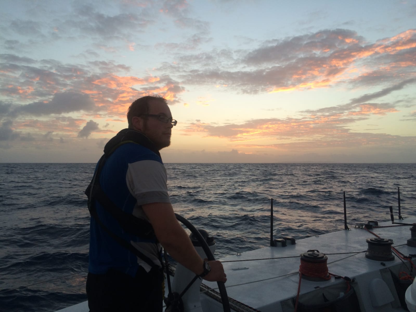 Ken at the helm of Challenger in calm seas at sunset, day 9 or 10 of the passage