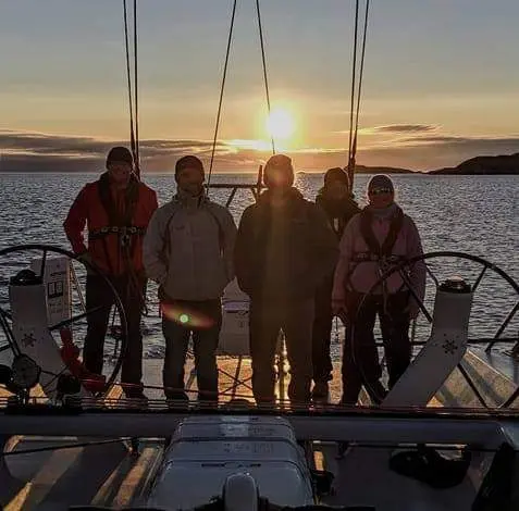 Crew silhouetted at twin helms during sunset