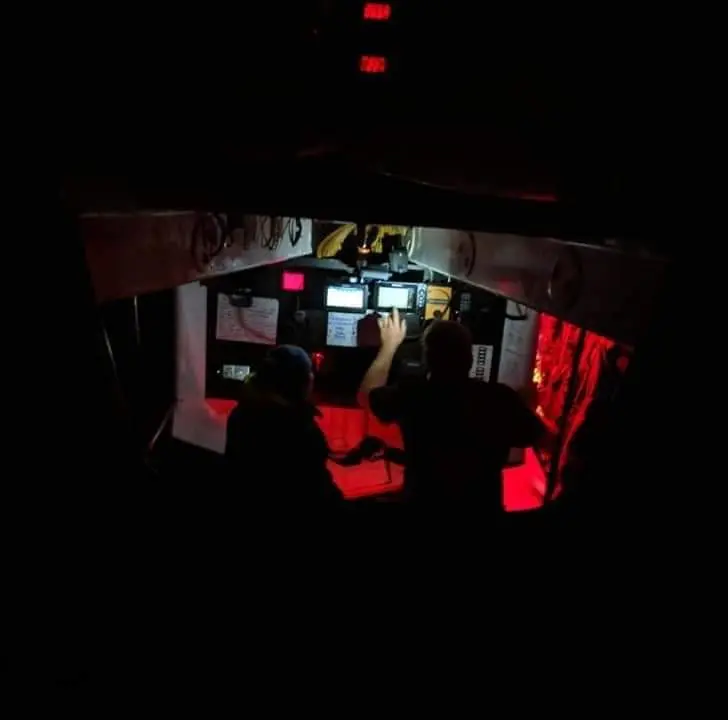 Red-lit navigation station at night during an offshore passage
