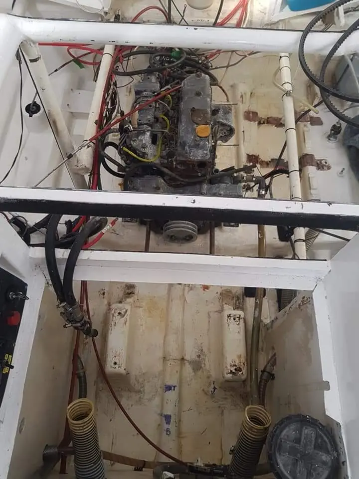 Engine bay mid-restoration with old paint and corrosion scraped away by hand