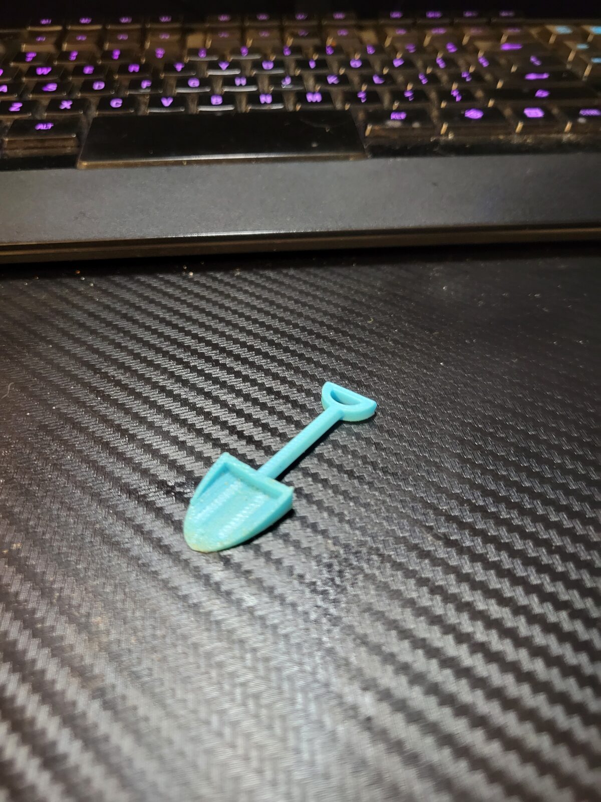 A teal 3D-printed herb-buster scoop